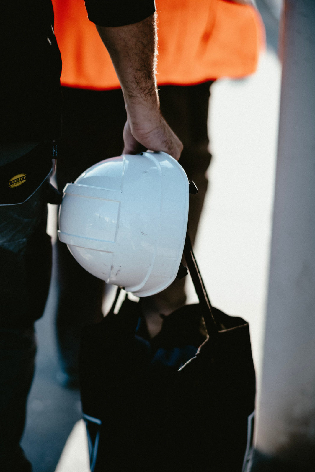 person carrying hard hat and bag